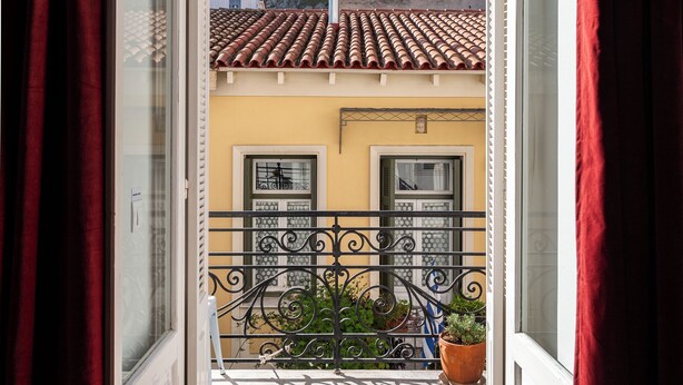 A balcony with a view of a building with a tiled roof and a mountain in the background. - Athenian Getaway Villa by Athenian Homes (Athens)