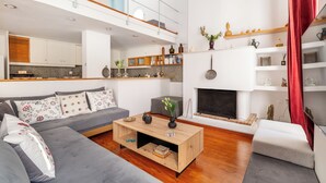 A modern living room with a grey sofa, a wooden coffee table, and a fireplace. - Athenian Getaway Villa by Athenian Homes (Athens)