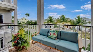 A balcony with a wooden bench and a potted plant.