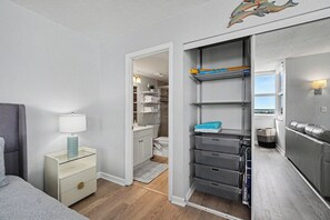 Een slaapkamer met een bed, nachtkastje en een kledingkast met planken en lades.