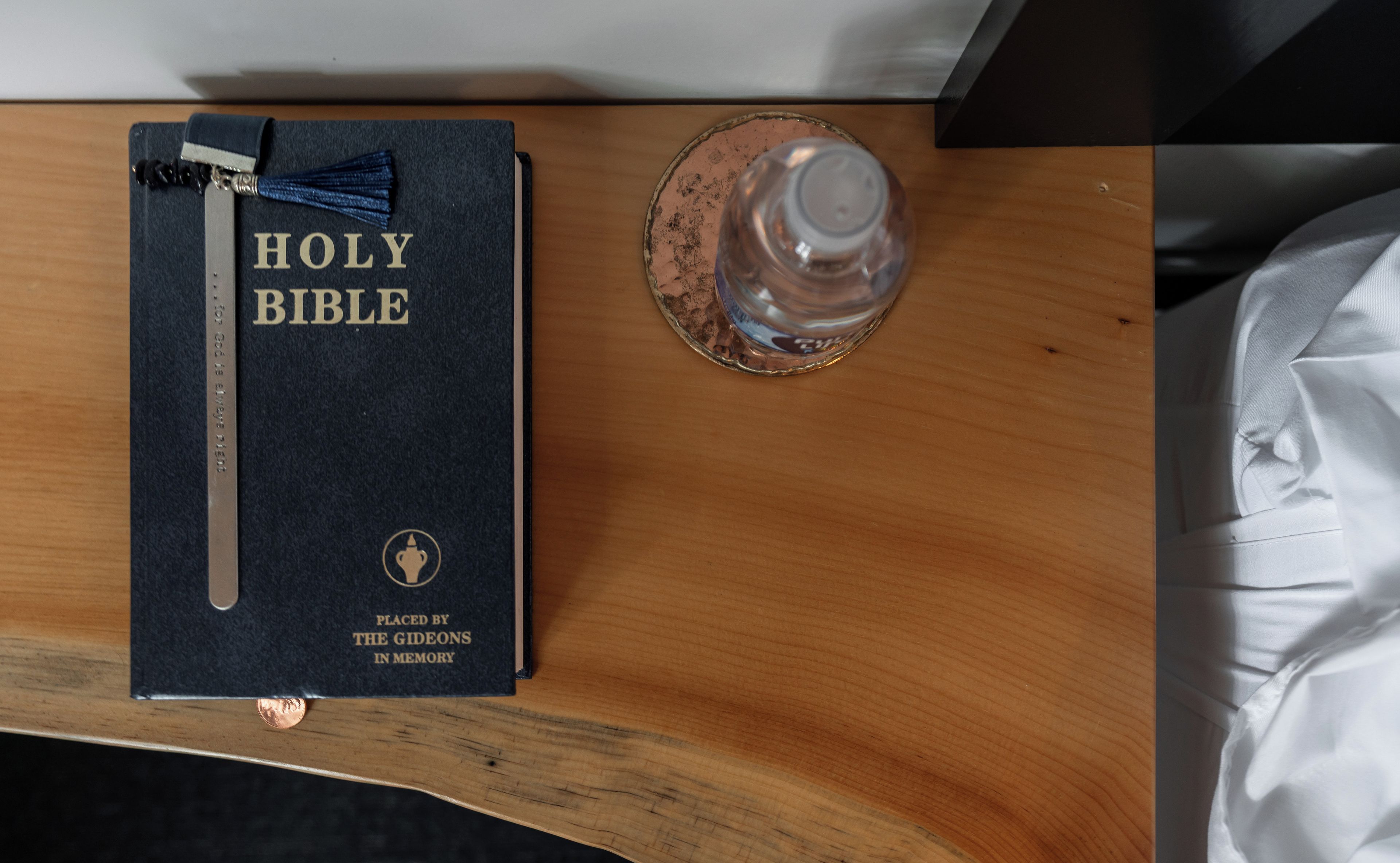 Una Biblia sobre una superficie de madera, junto a un vaso de agua.