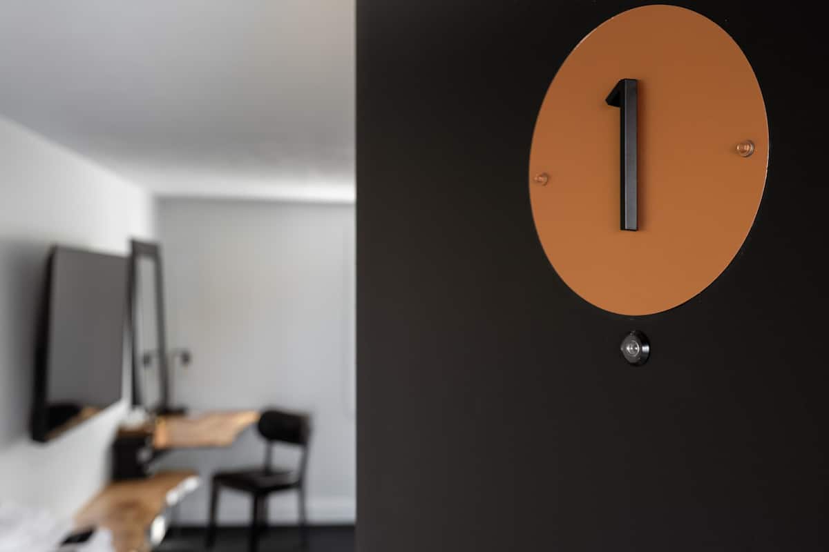 Ein modernes Hotelzimmer im minimalistischen Stil mit einem großen Bett, einem Schreibtisch und einem Stuhl.