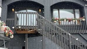 Ein zweistöckiges Gebäude mit Holzfassade, einem Balkon mit Geländer und einer Treppe, die zum oberen Stockwerk führt.