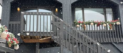 Un edificio de dos pisos con fachada de madera, un balcón con barandillas y una escalera que lleva al nivel superior.