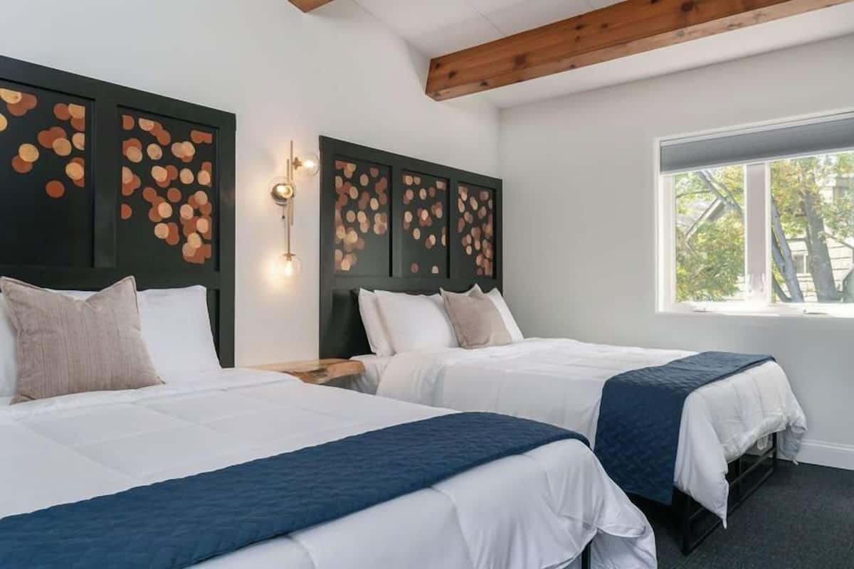 Ein Hotelzimmer mit zwei Betten, einem großen Fenster und einer Wand mit kreisförmigen Mustern.
