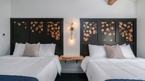 Ein Hotelzimmer mit zwei Betten, einem Holfnachtkästchen und einer wandmontierten Lampe.