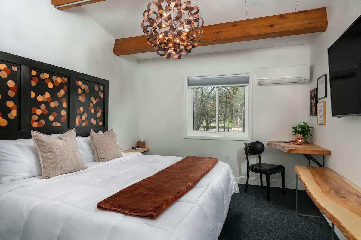 Ein Schlafzimmer mit Bett, Schreibtisch, Stuhl, Fenster und Deckenleuchte.