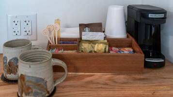 A wooden tray with coffee cups, a coffee machine, and various coffee pods.