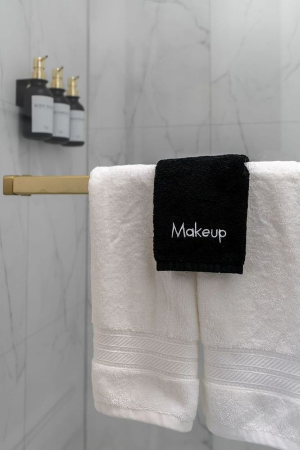 Una toalla blanca con una etiqueta negra que dice "Makeup" colgada en un perchero.