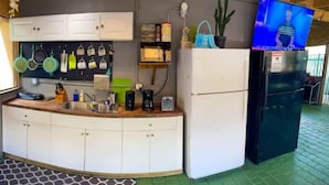 A compact kitchen with white cabinets, a black refrigerator, and a coffee maker on the counter. - Art Gardens Wynwood (Miami)