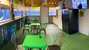 A small kitchen with a refrigerator, a sink, and a window. There are several chairs and a table in the room. - Art Gardens Wynwood (Miami)