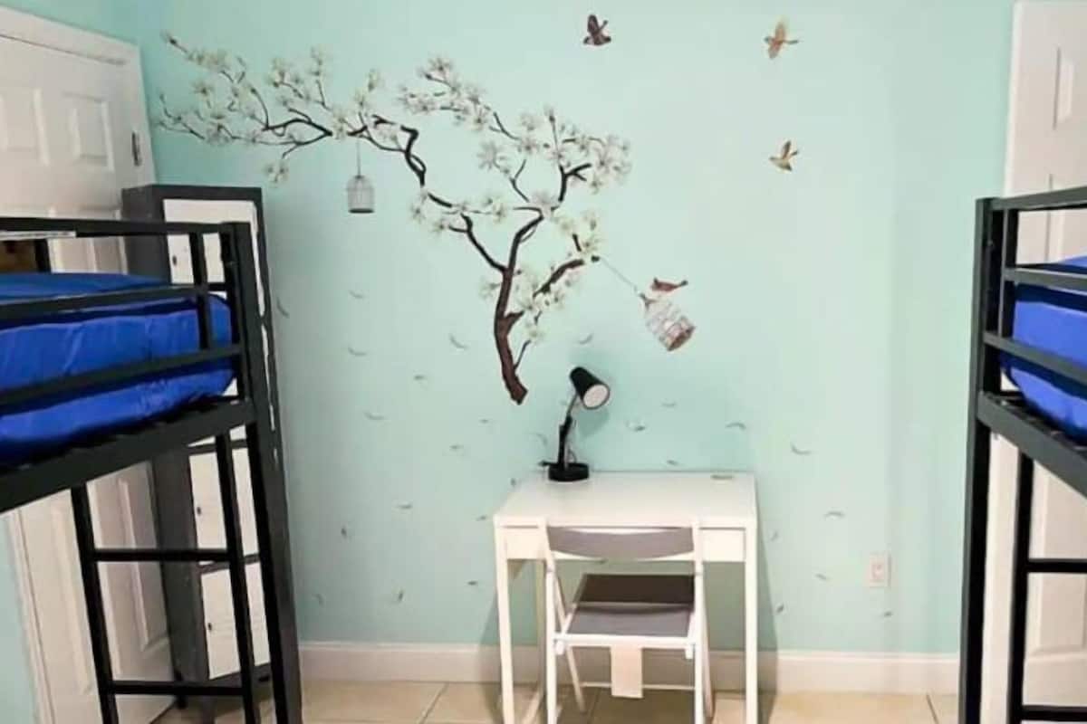 Una habitación con literas, un escritorio y un mural en la pared.