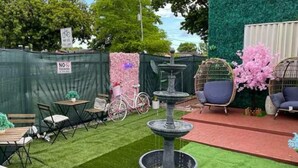 A patio area with a fountain, seating, and a bicycle. - Art Gardens Wynwood (Miami)