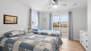 A bedroom with two beds, a ceiling fan, a window with curtains, and a view of the outside. - Attractive, updated 2-bedroom home, 5 min walk to beach, pets ok, onsite parking (Hampton)