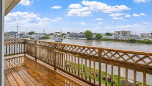 A wooden deck with a view of a river and buildings in the distance. - Attractive, updated 2-bedroom home, 5 min walk to beach, pets ok, onsite parking (Hampton)