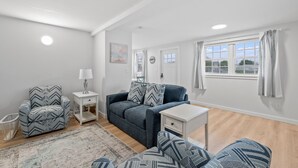 A modern living room with a grey sofa, matching armchair, and a small white table. - Attractive, updated 2-bedroom home, 5 min walk to beach, pets ok, onsite parking (Hampton)