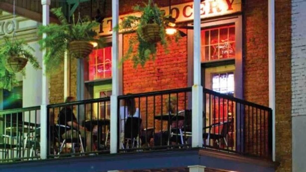 Un restaurante con terraza y plantas colgantes.