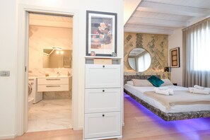 A bedroom with a bed, a dresser, a mirror, and a bathroom with a sink and toilet.