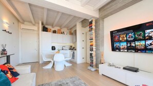 Ein modernes Wohnzimmer mit Küche, Essbereich und einem an der Wand befestigten Netflix-Display.
