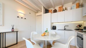 Eine moderne Küche mit weißen Schränken, einem runden Marmortisch und weißen Stühlen.