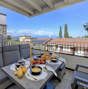 A dining area with a table set for a meal, overlooking a cityscape with buildings and trees.