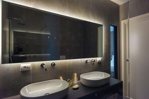 A modern bathroom with two large sinks, a large mirror, and a shower area.