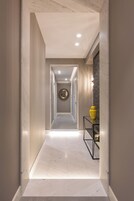 A modern hallway with a marble floor, a round mirror on the wall, and a yellow vase on a black console table.
