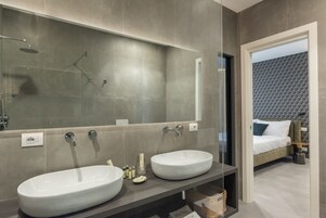 A modern bathroom with two large white sinks, a glass shower enclosure, and a large mirror.