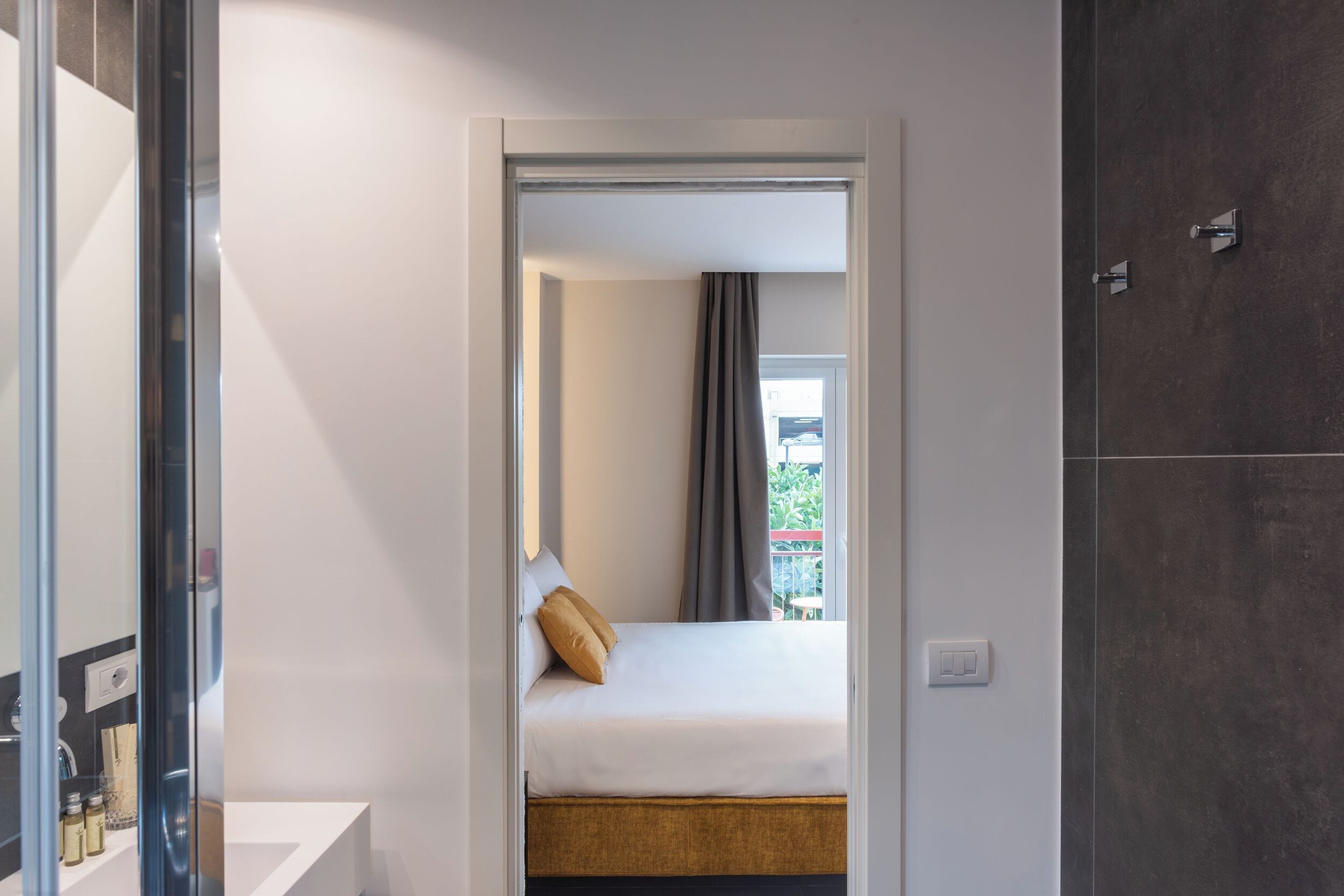 A modern hotel room with a bed, a small bedside table, and a large mirror.