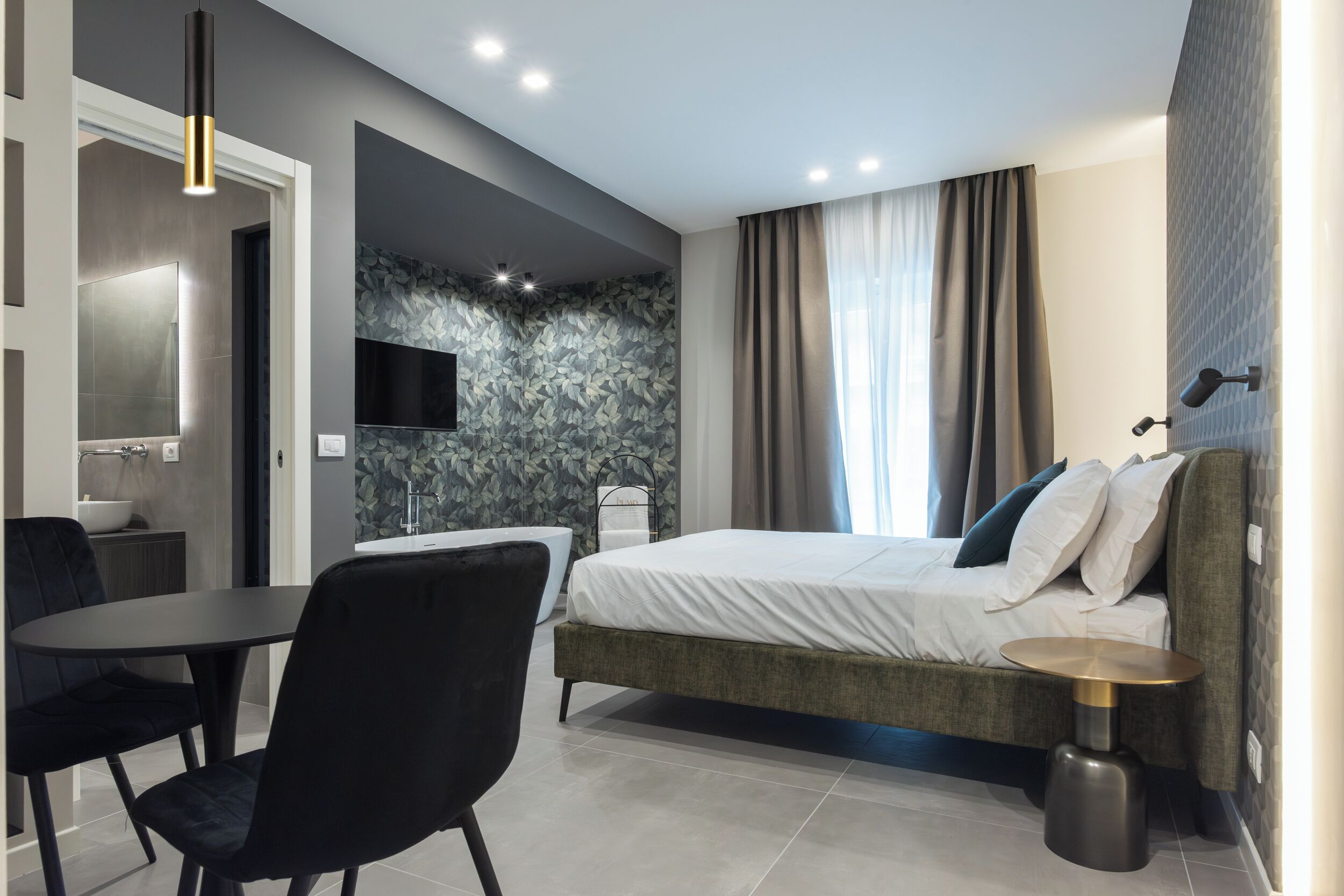 Un dormitorio moderno con cama, mesita de noche y televisión montada en la pared.