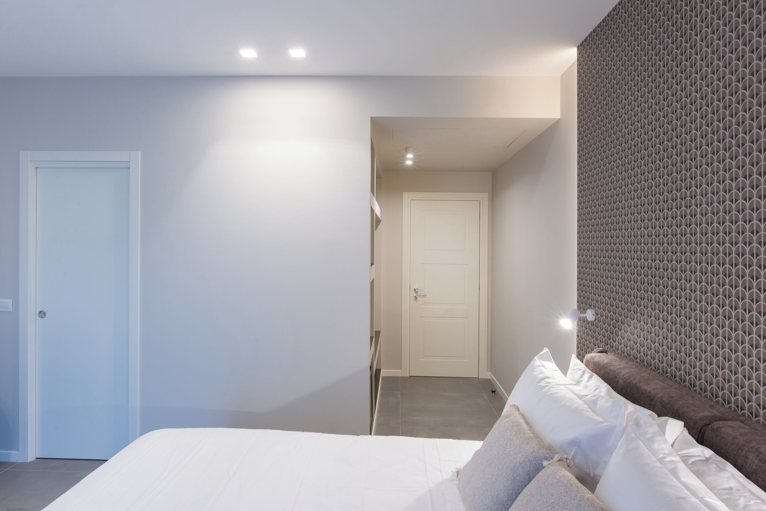 Ein modernes Schlafzimmer mit Bett, Tür und einer Wand mit Muster.