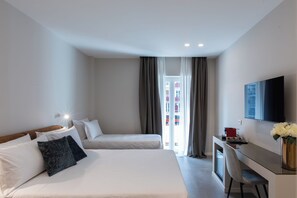 A hotel room with two beds, a desk, a chair, a TV, and a window with curtains.