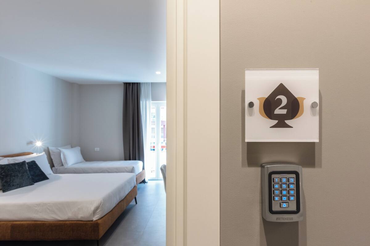 Una camera d'albergo con un letto, un cartello appeso al muro con il numero 2 e una serratura a combinazione.
