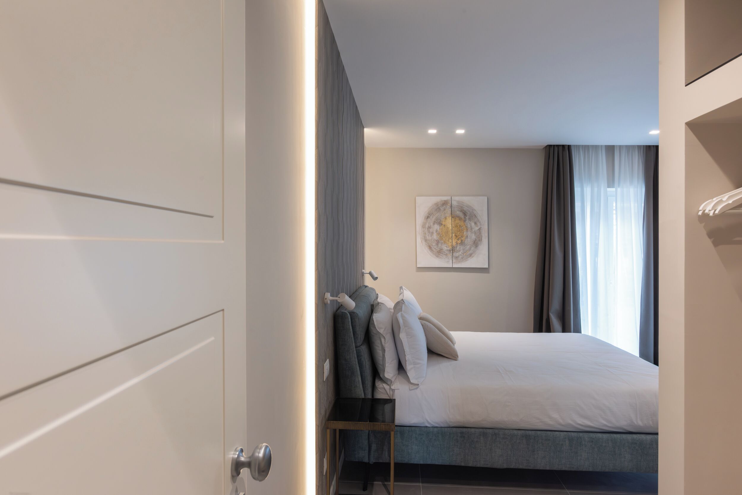 A modern bedroom with a bed, a side table, and a wall-mounted artwork.