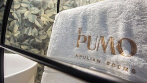En vit handduk med broderad text i guld: ”PUMO APULIAN ROOMS”.