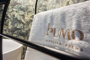 A white towel with "PUMO APULIAN ROOMS" embroidered in gold.