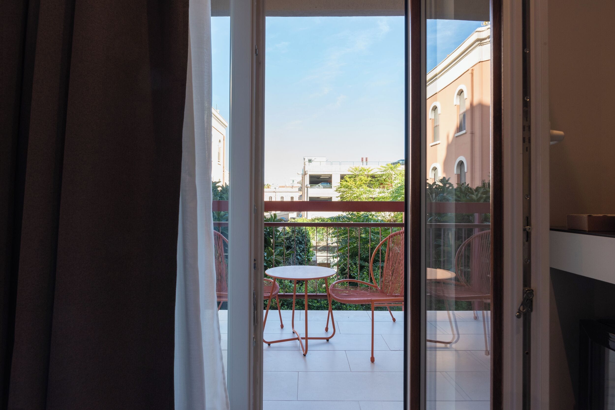 A balcony with a table and chairs, a view of buildings, and a clear sky.