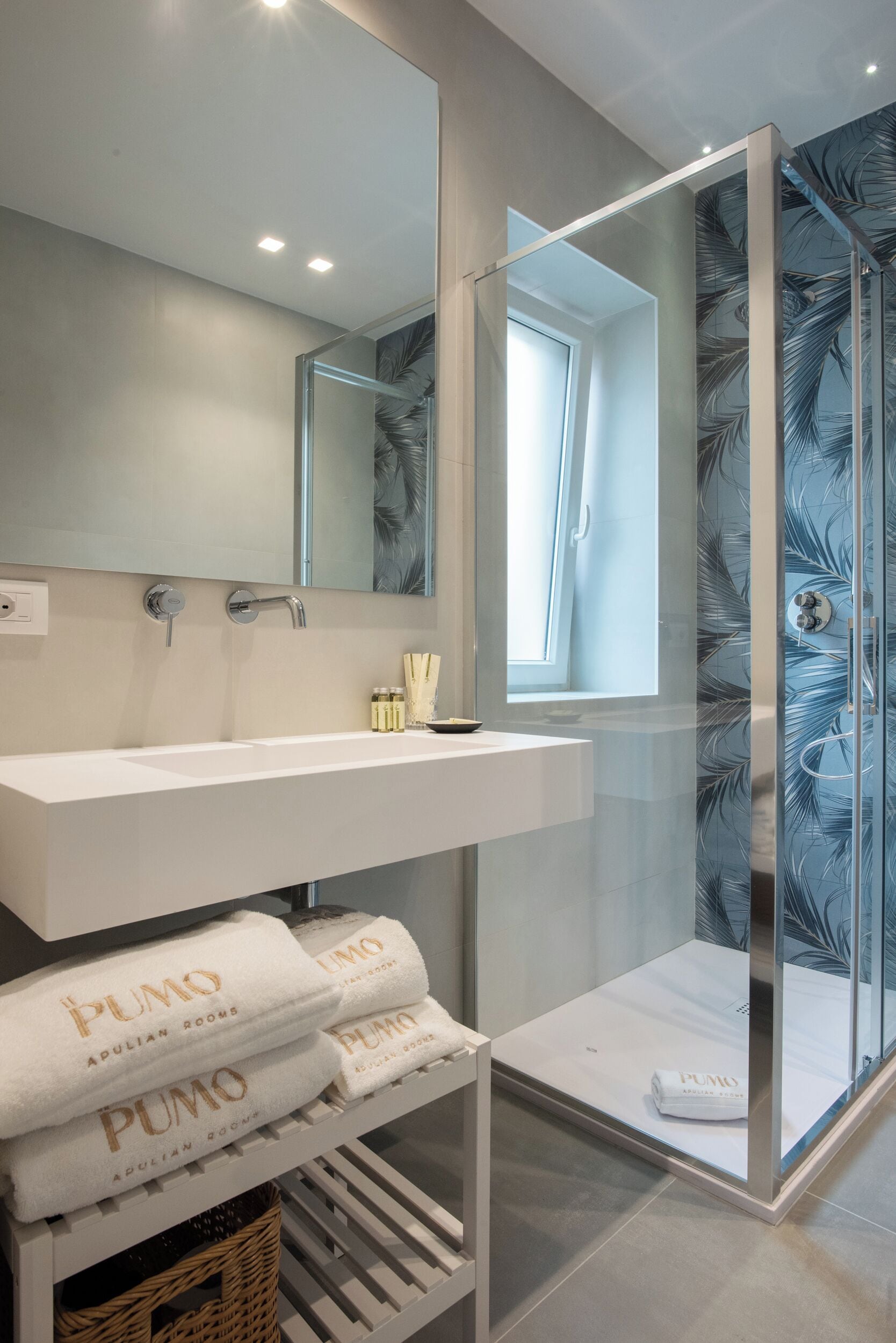 A modern bathroom with a white vanity, a large mirror, and a glass-enclosed shower.