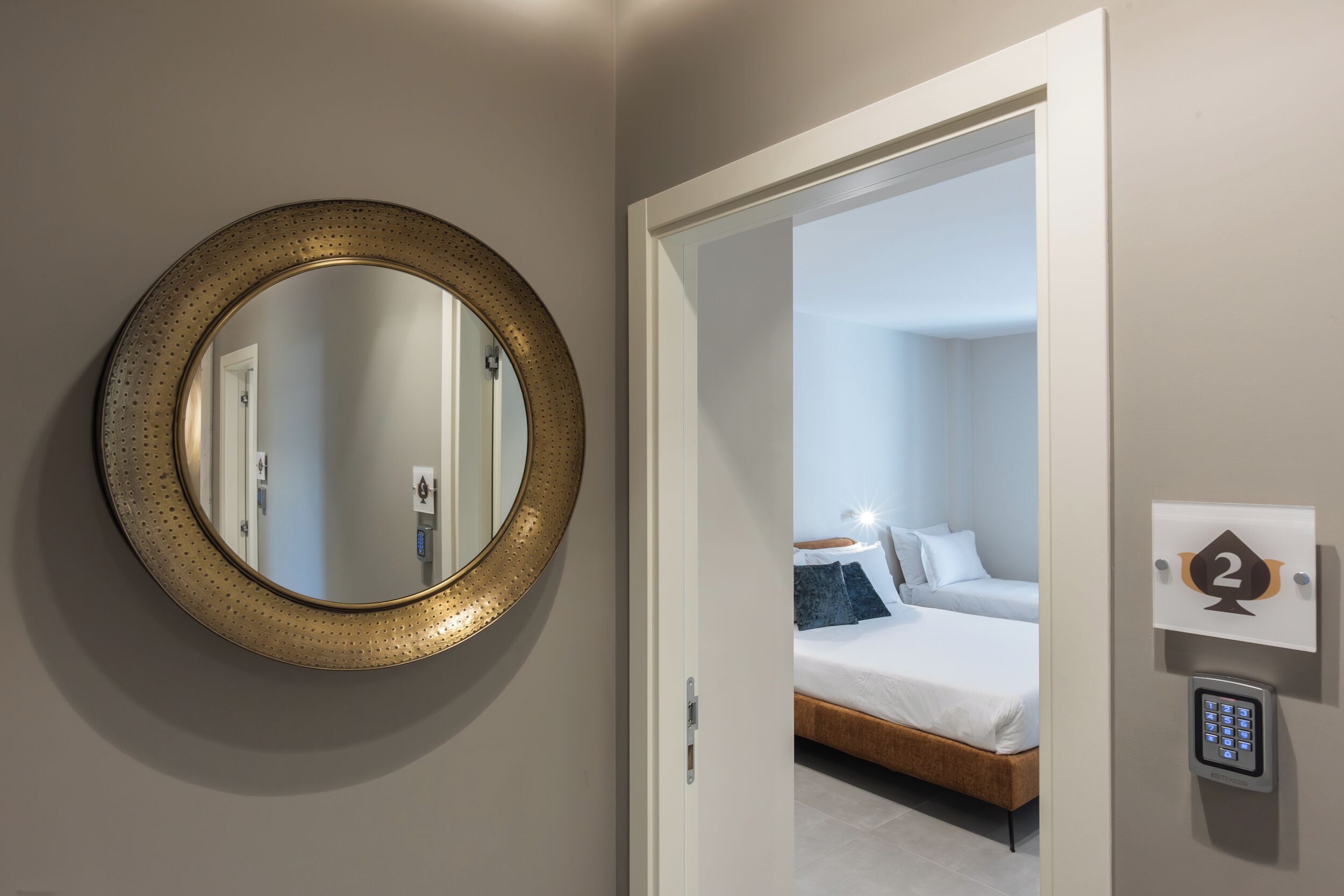 Une pièce avec un miroir rond, un lit et une porte donnant sur une autre pièce.