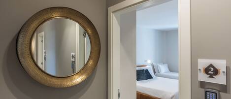 Une pièce avec un miroir rond, un lit et une porte donnant sur une autre pièce.