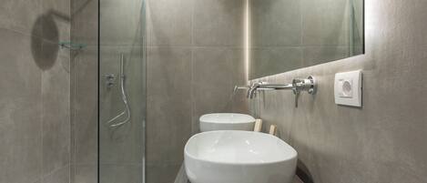 A modern bathroom with a glass shower enclosure, a large white sink, and a mirror.