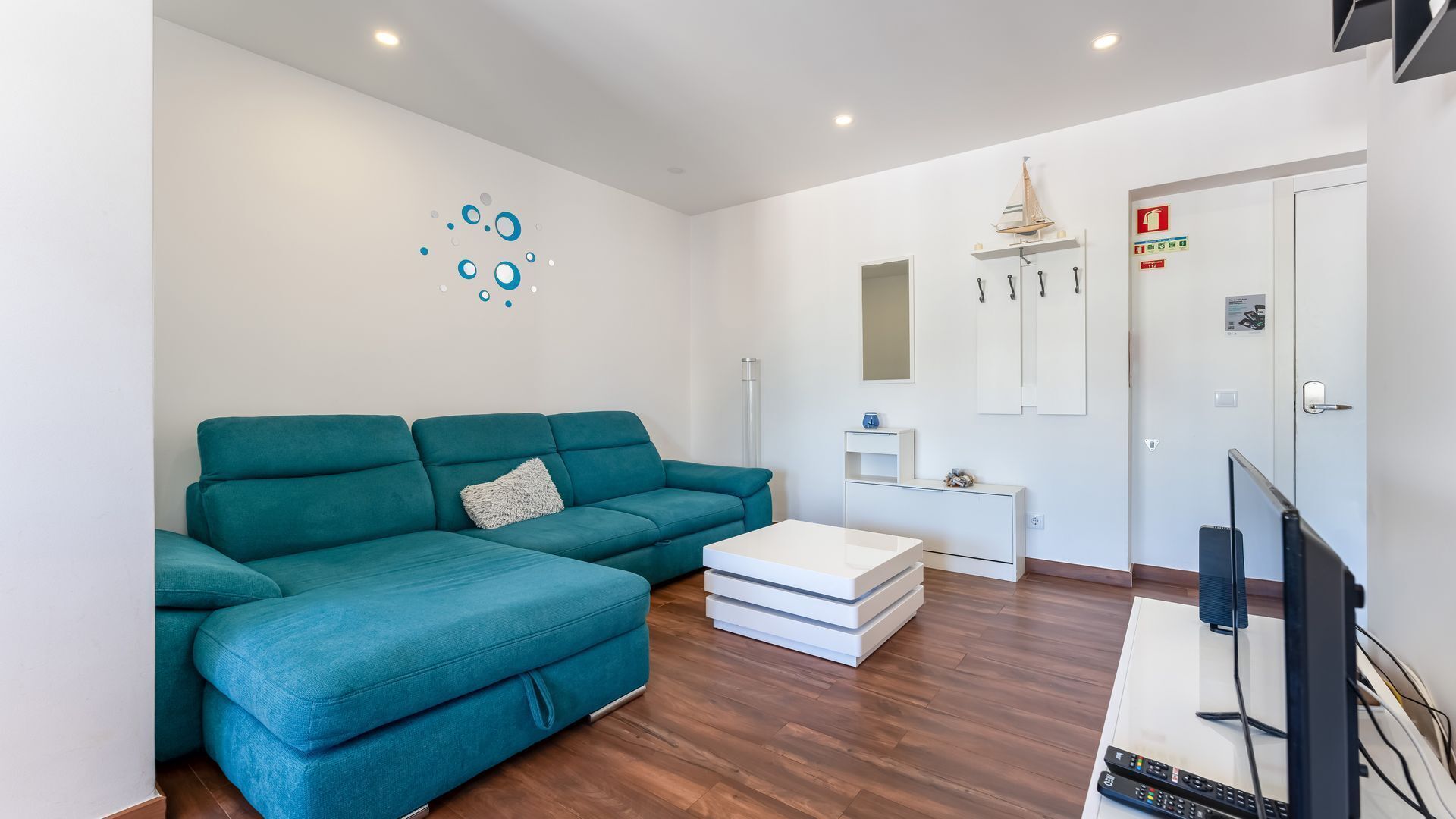 Relax in the cozy living room, complete with a plush teal sofa – ideal for unwinding after a day in the Algarve.
#CozyVibes #RelaxInStyle #SereneBlueFlat