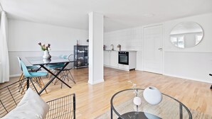 Un espacio moderno y abierto para sala y comedor, con cocina, piso de madera y un espejo grande.