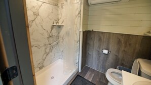 Ein Badezimmer mit Dusche, Toilette und Marmorwänden.