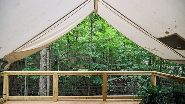 Eine Holzterrasse mit Geländer, umgeben von einem Wald.