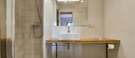 Een badkamer met een douche, een wastafel met spiegel en een toilet.