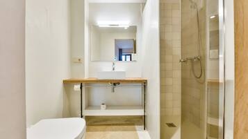 A modern bathroom with a toilet, sink, and shower.