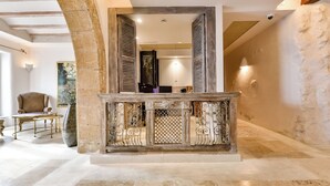 Un arc en pierre mène à un espace d’accueil doté d’un comptoir en bois et d’un grand miroir.