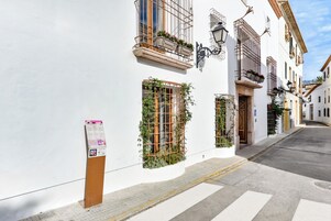 Un edificio blanco con balcones, una calle y un paso de peatones.