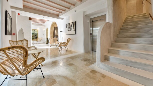 Un intérieur spacieux agrémenté d’un escalier en marbre, de meubles en osier et d’un design moderne.